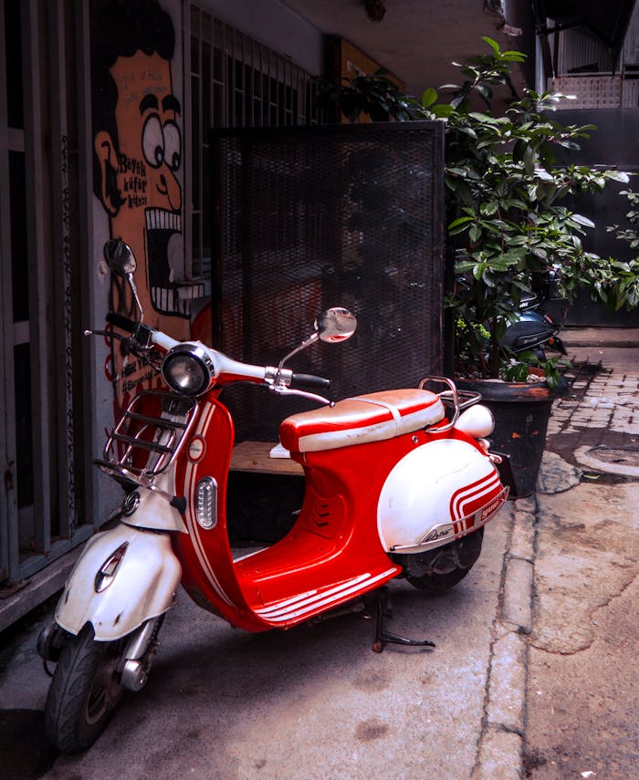 a-red-and-white-motor-scooter-parked-on-the-street-13575269 A classic red and white scooter parked on a city street near urban art.