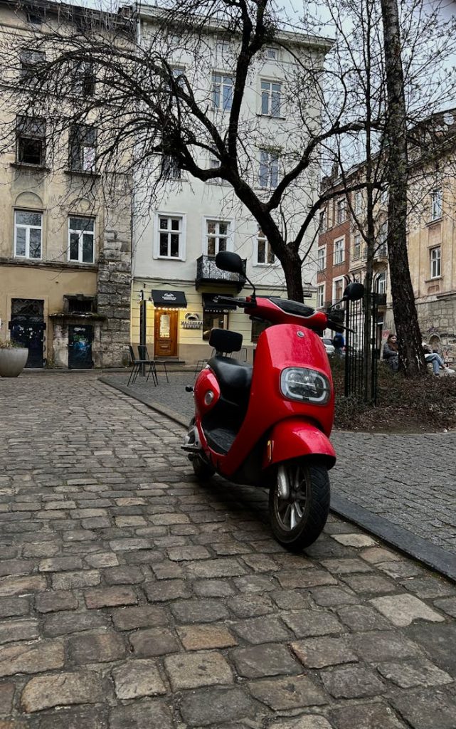 red-electric-scooter-on-cobblestone-street-31477305 A red electric scooter parked on a cobblestone street in a historic European town.